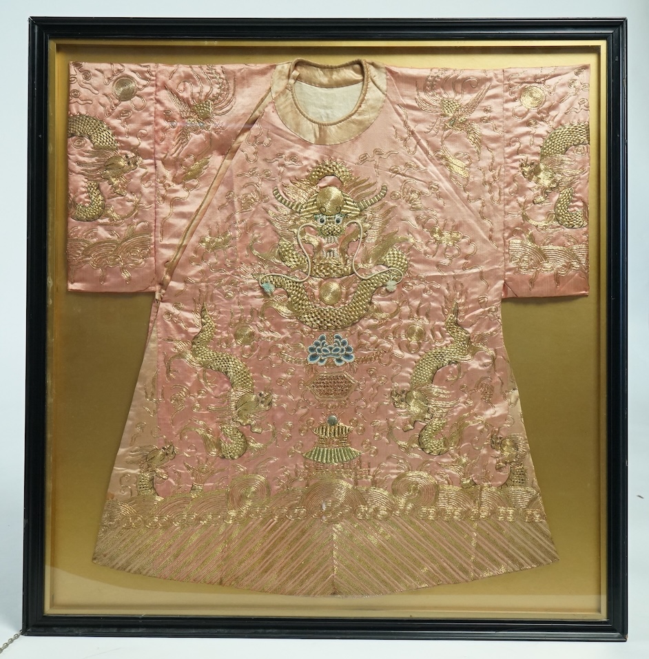 A framed late 19th early 20th century Chinese pink silk and gold embroidered dragon jacket. The dragons embroidered with raised couched gold thread work, surrounded by Phoenix and auspicious symbols. Jacket 69cm wide x 7